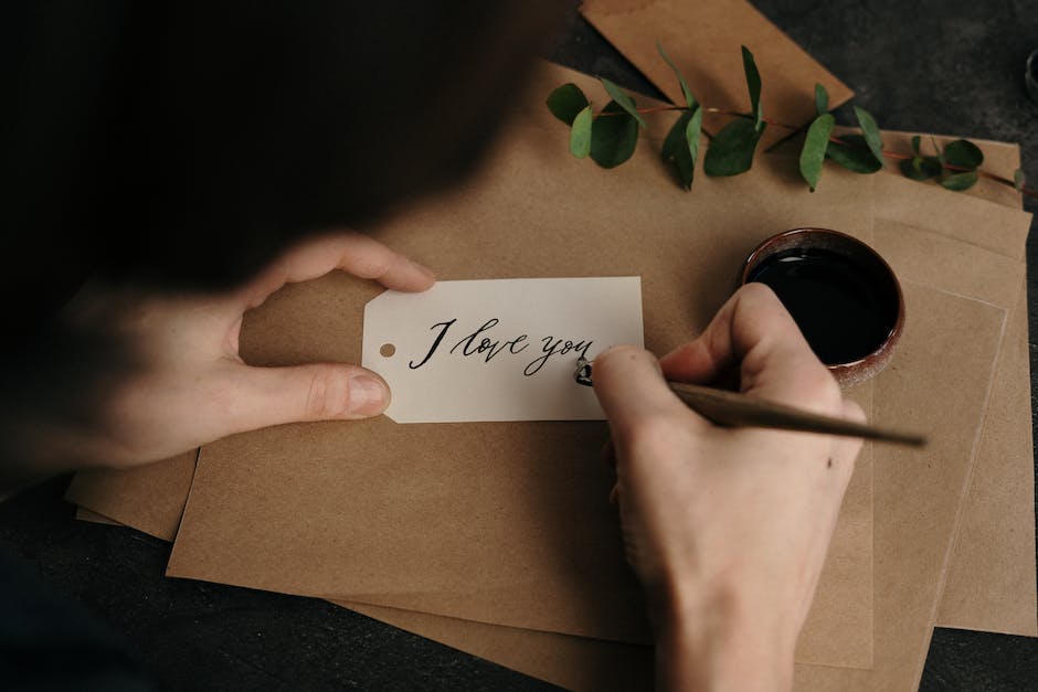 A hand holding a pen and writing a thank you note to represent follow-up etiquette.