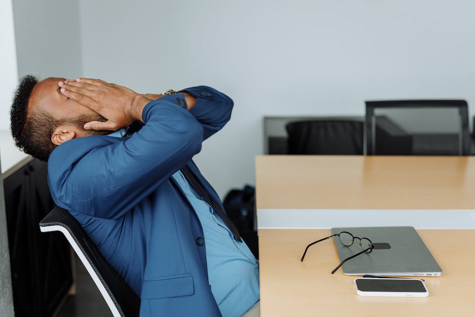 An image of a person sitting at a desk with their head in their hands, showcasing the stress of everyday life.